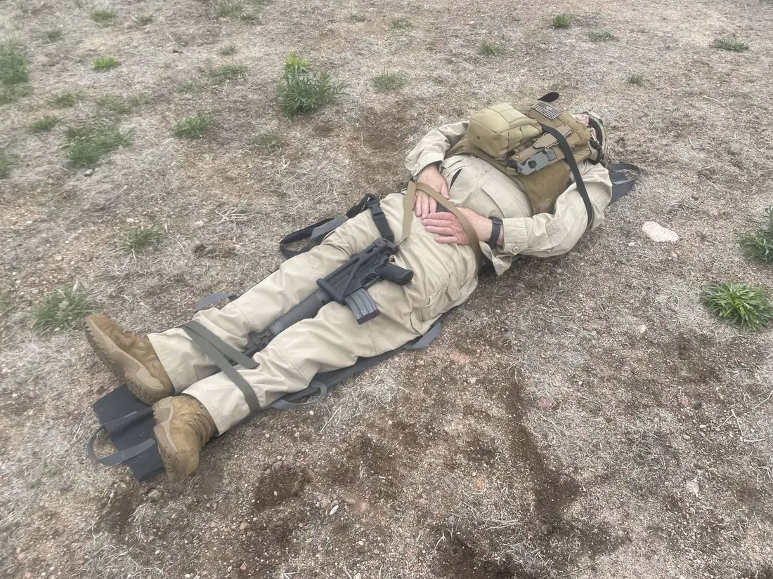 Casualty in full kit lying on a deployed Pocket Litter, full body view